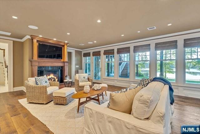 living room with a premium fireplace, recessed lighting, wood finished floors, and crown molding