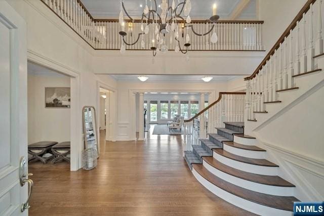 entryway with stairs, ornamental molding, wood finished floors, and a decorative wall