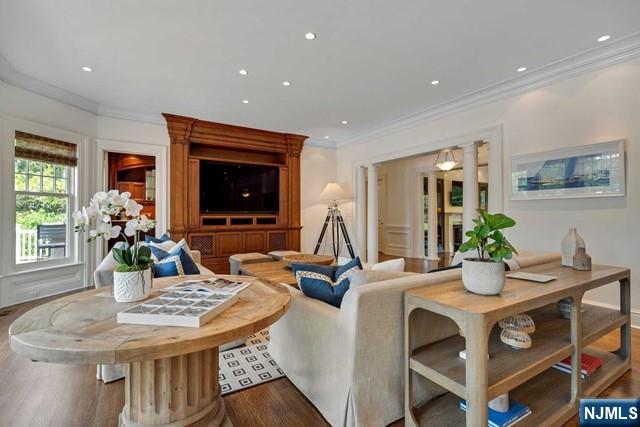 living area featuring ornate columns, crown molding, wood finished floors, and recessed lighting