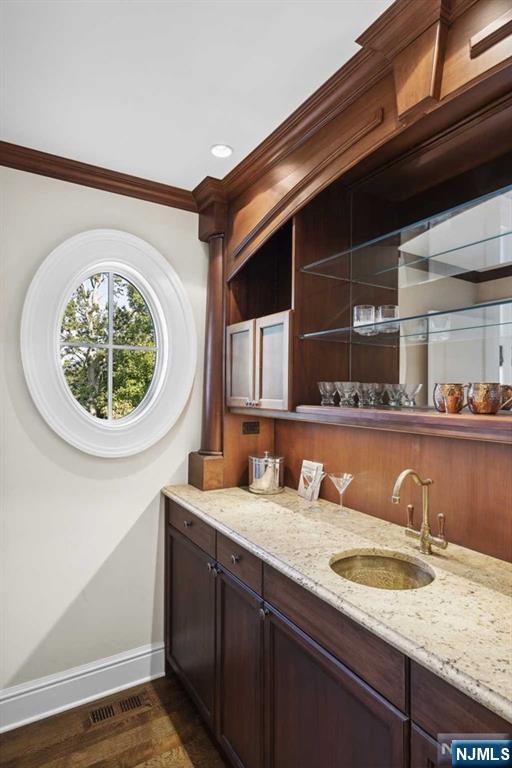 bathroom featuring baseboards, visible vents, ornamental molding, wood finished floors, and vanity