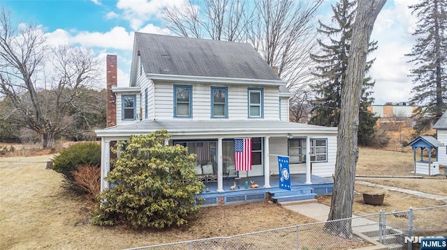 view of front of home with covered porch, a chimney, fence private yard, and a gate