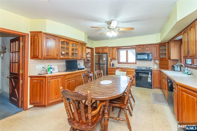 kitchen featuring light floors, brown cabinets, a sink, and black appliances