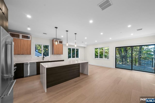 kitchen featuring light countertops, visible vents, appliances with stainless steel finishes, a kitchen island, and modern cabinets