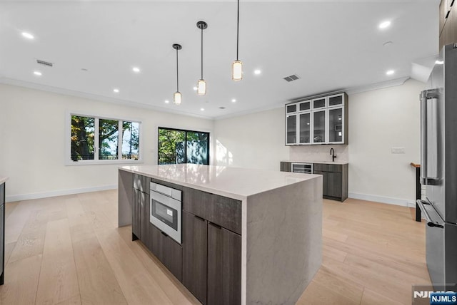 kitchen featuring visible vents, light wood-style flooring, ornamental molding, modern cabinets, and high end refrigerator