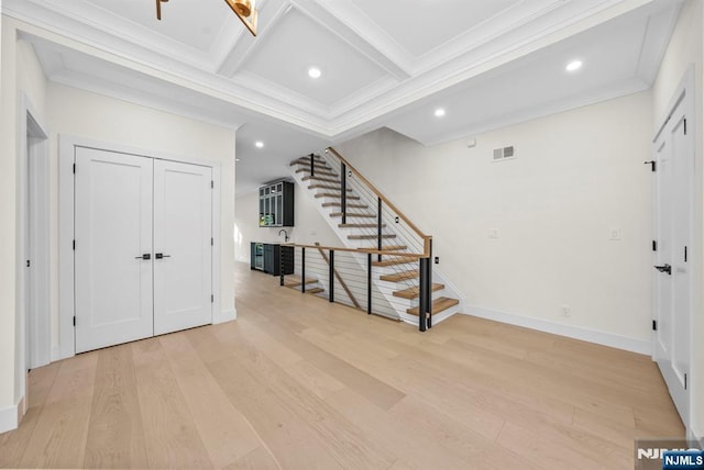 foyer featuring visible vents, stairway, ornamental molding, light wood-type flooring, and coffered ceiling