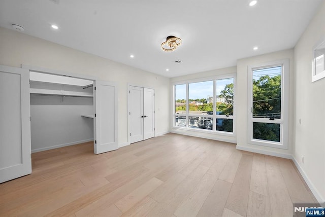 unfurnished bedroom featuring light wood finished floors, multiple closets, recessed lighting, visible vents, and baseboards