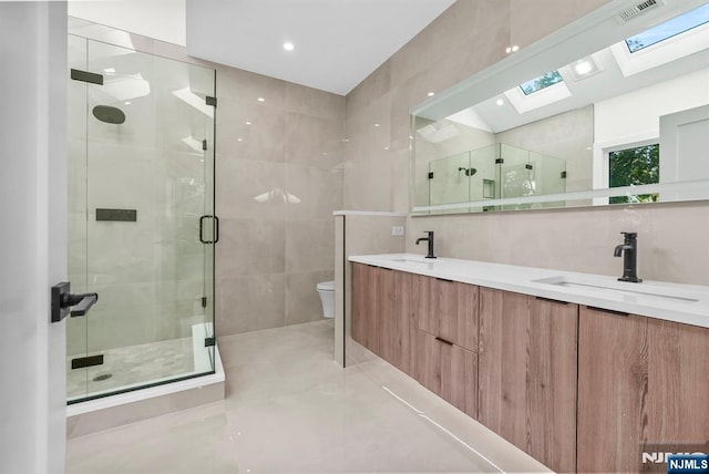 full bath featuring a sink, visible vents, tile walls, double vanity, and a stall shower