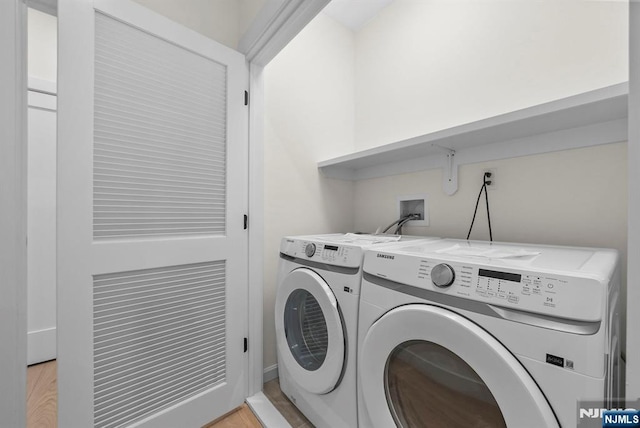 laundry room with laundry area, washing machine and dryer, and light wood finished floors