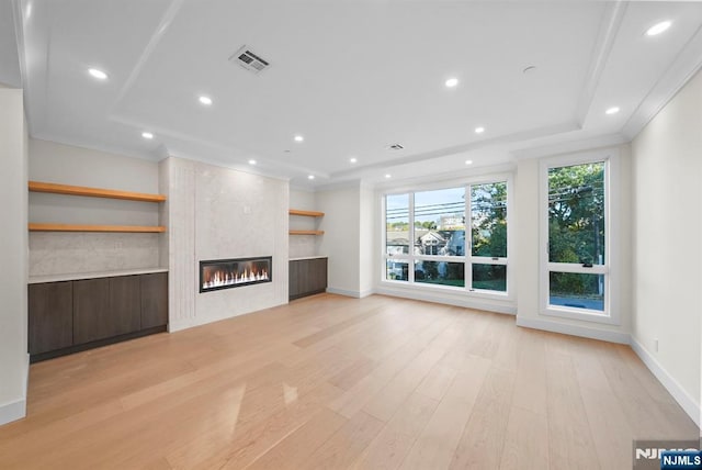 unfurnished living room with ornamental molding, visible vents, light wood-style flooring, and a tiled fireplace