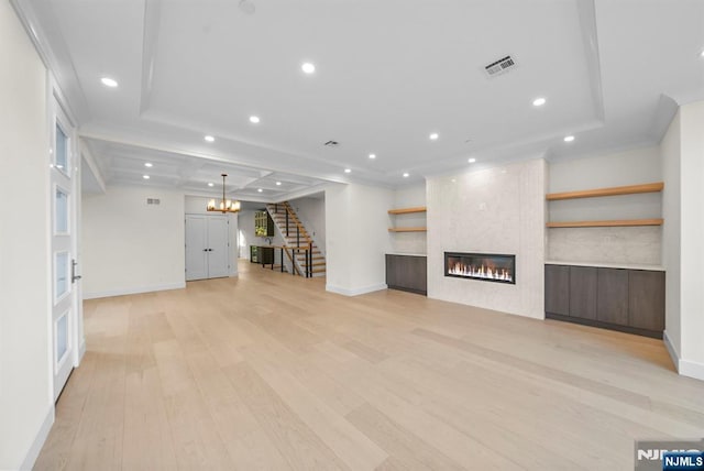 unfurnished living room featuring light wood-style flooring, recessed lighting, a large fireplace, and stairway