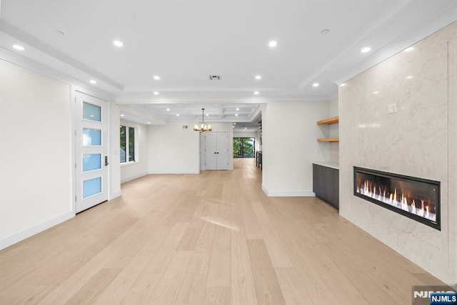 unfurnished living room featuring light wood finished floors, a fireplace, a raised ceiling, and recessed lighting