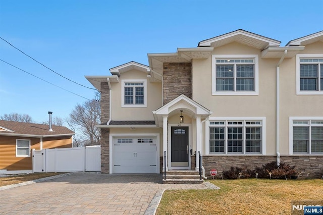 view of front of property with an attached garage, fence, stone siding, decorative driveway, and stucco siding