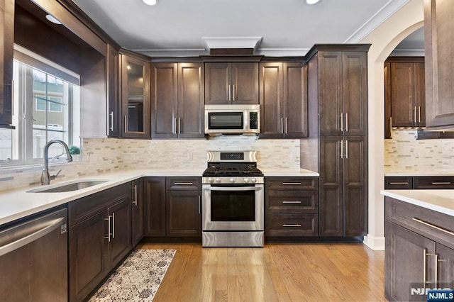 kitchen featuring light countertops, appliances with stainless steel finishes, a sink, and dark brown cabinetry