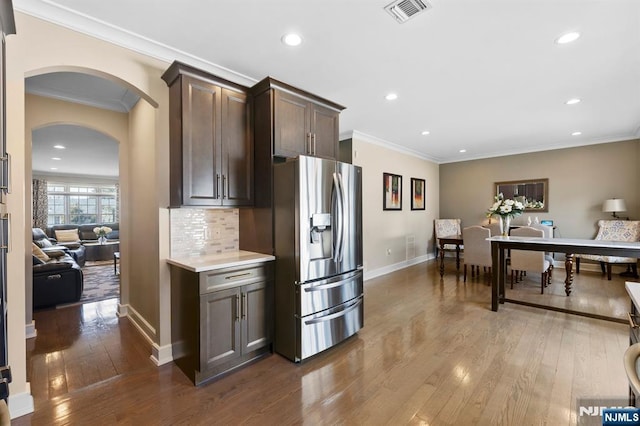 kitchen with dark wood-style flooring, light countertops, visible vents, backsplash, and stainless steel fridge