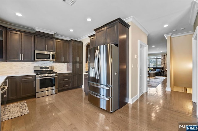 kitchen featuring stainless steel appliances, wood finished floors, light countertops, and dark brown cabinetry