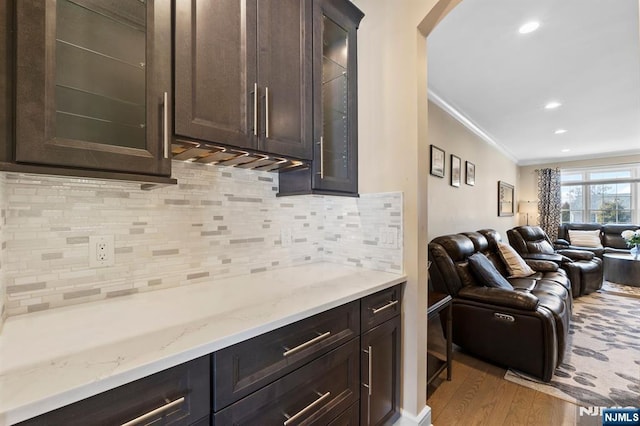 kitchen with crown molding, open floor plan, dark brown cabinets, and wood finished floors