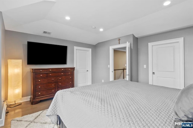 bedroom with lofted ceiling, recessed lighting, wood finished floors, visible vents, and baseboards