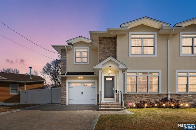 view of front of house featuring stone siding, decorative driveway, and stucco siding