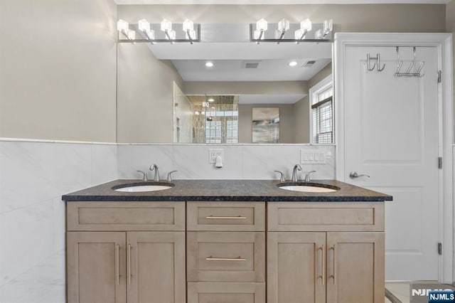 full bathroom with a sink, tile walls, and double vanity