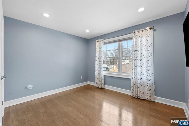 spare room with baseboards, wood finished floors, and recessed lighting