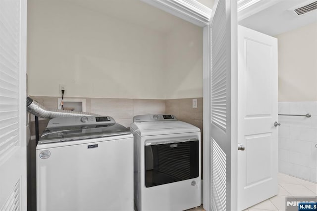 laundry room featuring a wainscoted wall, laundry area, visible vents, washer and dryer, and tile walls