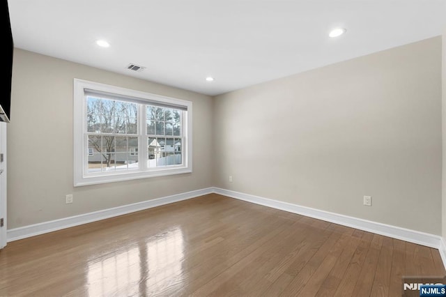 unfurnished room with recessed lighting, visible vents, baseboards, and wood finished floors