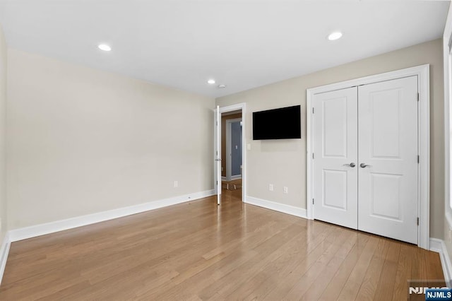 unfurnished bedroom with light wood-style flooring, baseboards, a closet, and recessed lighting