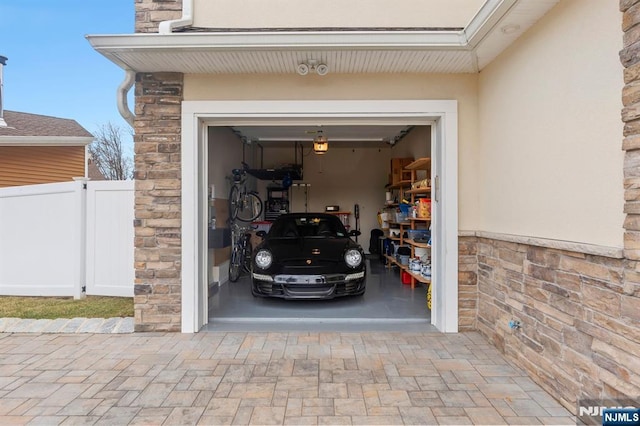 garage featuring fence and decorative driveway