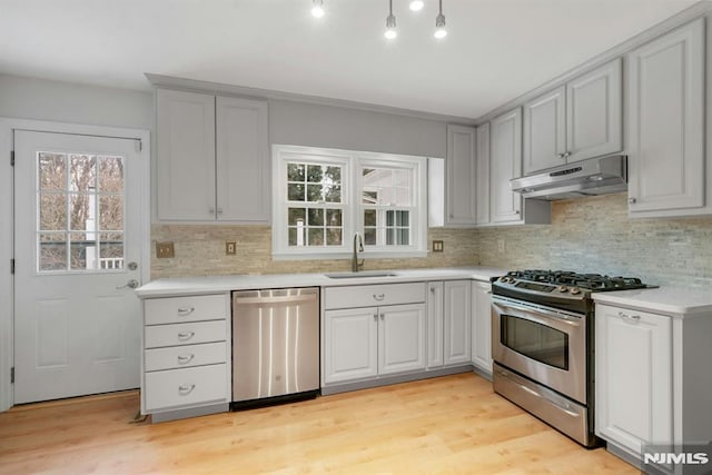 kitchen with under cabinet range hood, stainless steel appliances, a sink, and light countertops