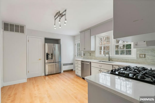 kitchen with visible vents, radiator, appliances with stainless steel finishes, light countertops, and a sink