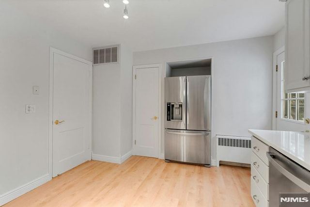 kitchen featuring radiator, light countertops, visible vents, appliances with stainless steel finishes, and light wood-style floors