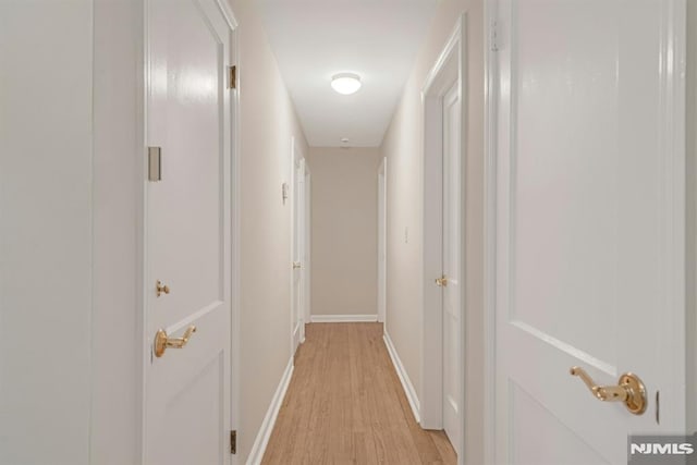 hallway with light wood-type flooring and baseboards