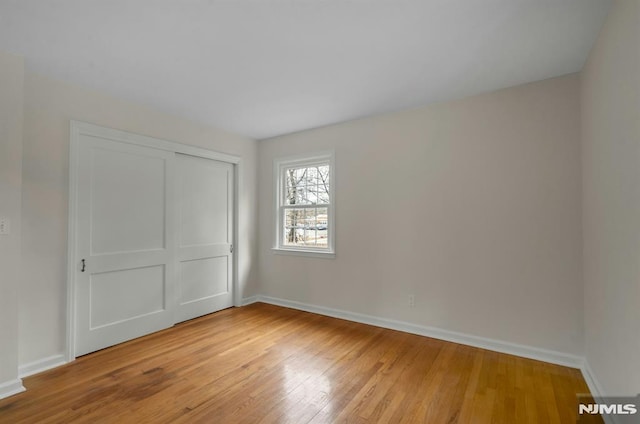 unfurnished bedroom featuring a closet, light wood-style flooring, and baseboards