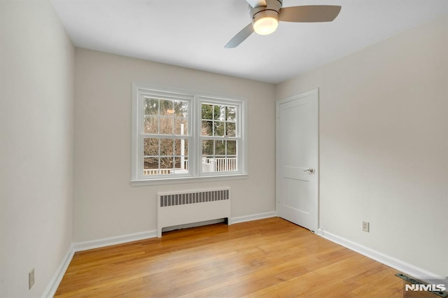 unfurnished room with baseboards, ceiling fan, wood finished floors, and radiator