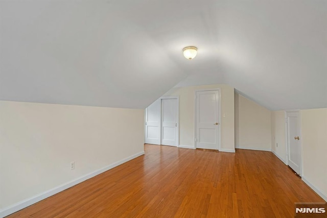 bonus room featuring baseboards, lofted ceiling, and light wood-style floors