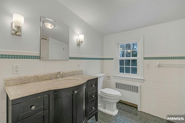 bathroom with toilet, vanity, tile walls, wainscoting, and radiator