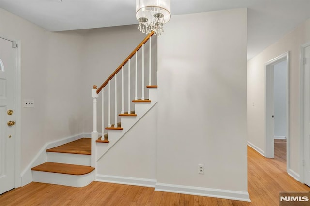 entryway with a chandelier, stairway, wood finished floors, and baseboards