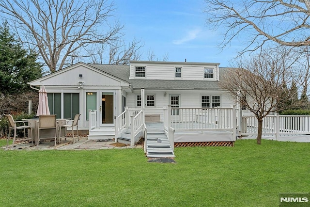 back of property with roof with shingles, a yard, a wooden deck, and a patio