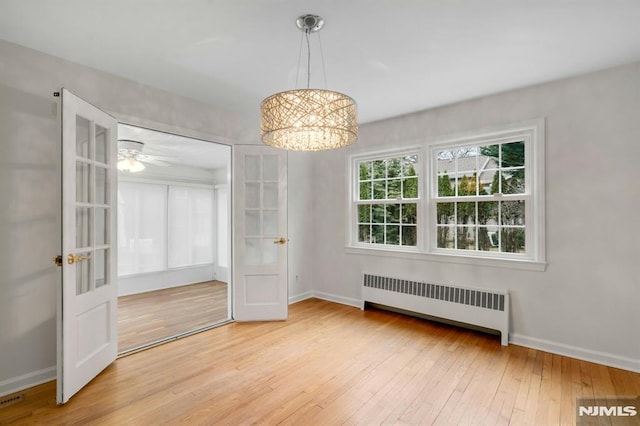 unfurnished dining area with radiator heating unit, baseboards, wood finished floors, and french doors