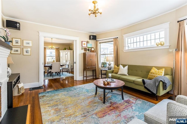 living area featuring a chandelier, plenty of natural light, hardwood / wood-style flooring, and crown molding