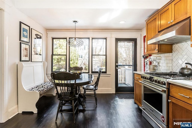 kitchen with under cabinet range hood, plenty of natural light, high end stainless steel range oven, and brown cabinets