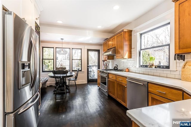 kitchen with stainless steel appliances, brown cabinetry, plenty of natural light, and under cabinet range hood