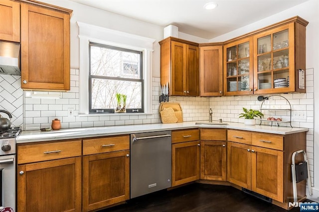 kitchen featuring brown cabinetry, stainless steel appliances, a sink, and light countertops