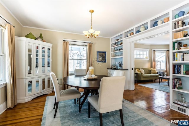 dining area with ornamental molding, a wealth of natural light, wood-type flooring, and a notable chandelier