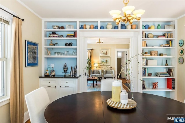 dining space featuring crown molding, built in features, and an inviting chandelier