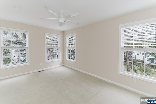 unfurnished room with light carpet, ceiling fan, visible vents, and baseboards