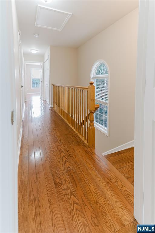 corridor featuring attic access, baseboards, an upstairs landing, and hardwood / wood-style flooring