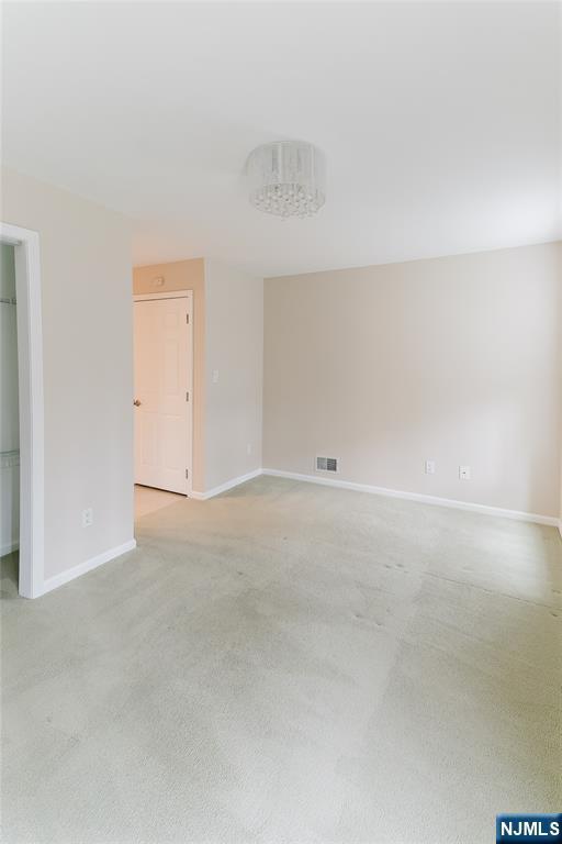 interior space featuring baseboards, visible vents, and light colored carpet