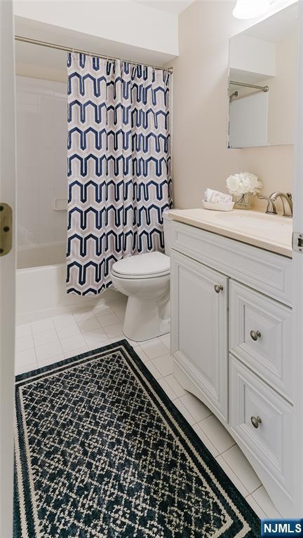 full bath with toilet, tile patterned flooring, shower / bathtub combination with curtain, and vanity