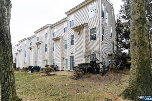 rear view of property featuring a lawn and a patio